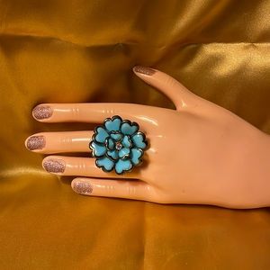 Adjustable turquoise look flower elastic ring w/gold back. Rhinestone in middle